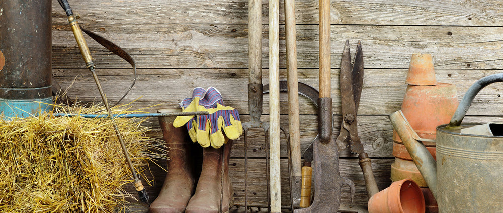 wooden wall with boots, pots, hay, and various tools leaning against it