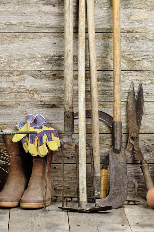 wooden wall with boots, pots, hay, and various tools leaning against it